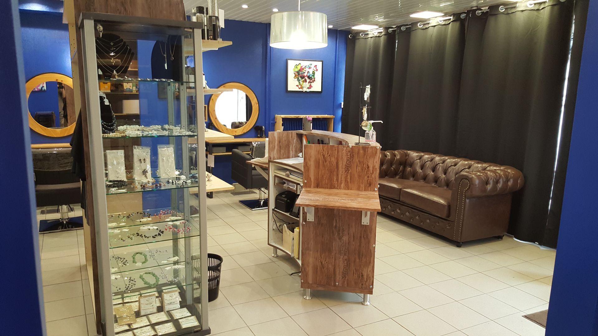 Partie de la salle d'attente du salon de coiffure avec étagère remplie de bijoux fantaisie en vente