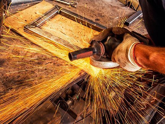 Un hombre está moliendo un trozo de metal con una amoladora.