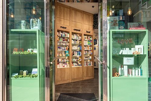 El interior de una farmacia con estantes verdes y una puerta de cristal.