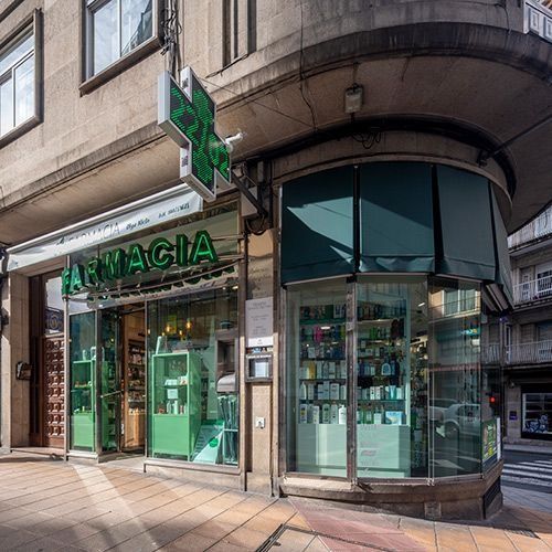 Una esquina de un edificio con un cartel verde que dice farmacia