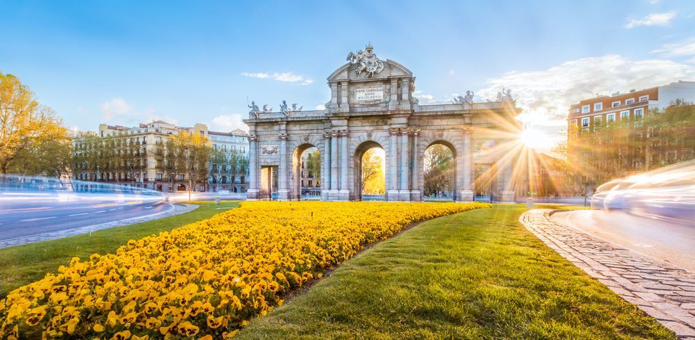 La Puerta de Alcalá, un monumento en Madrid, España, rodeada de vegetación y flores amarillas