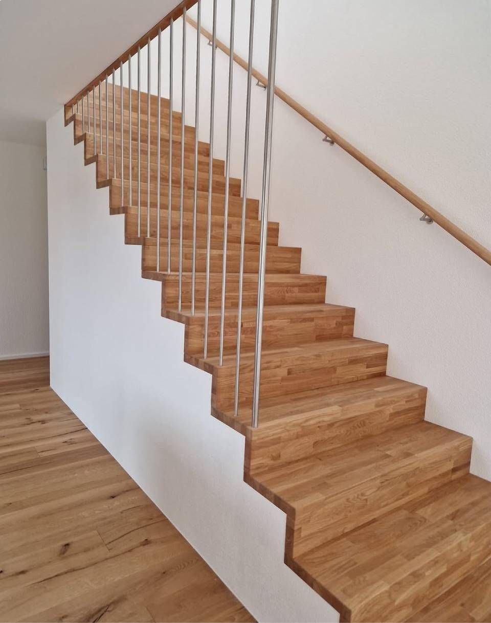 Holztreppe mit weissen Wänden und Handlauf in einem hellen Flur