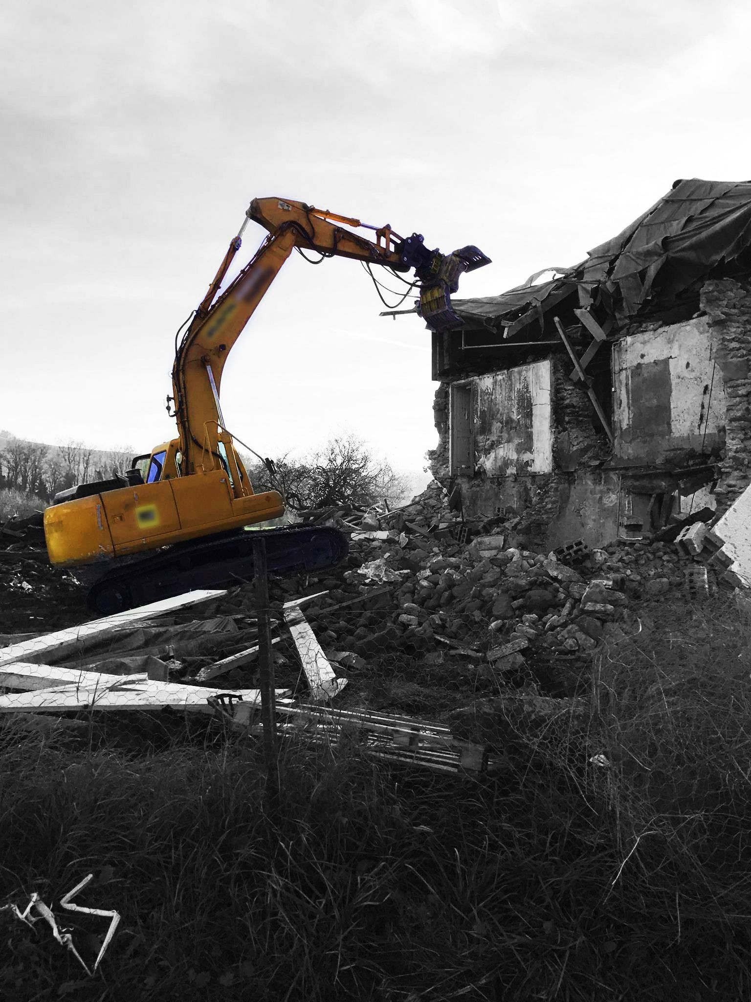Engin de démolition devant une vieille maison