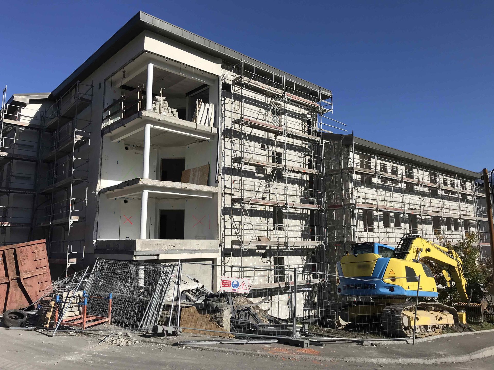 Engin jaune et bleu devant des échafaudages