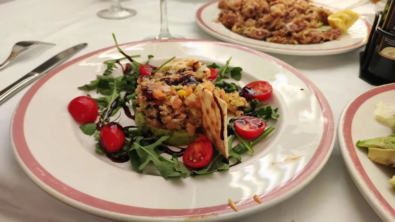 Ensalada de pollo a la parrilla con tomates y verduras en un plato blanco en la mesa de un restaurante.