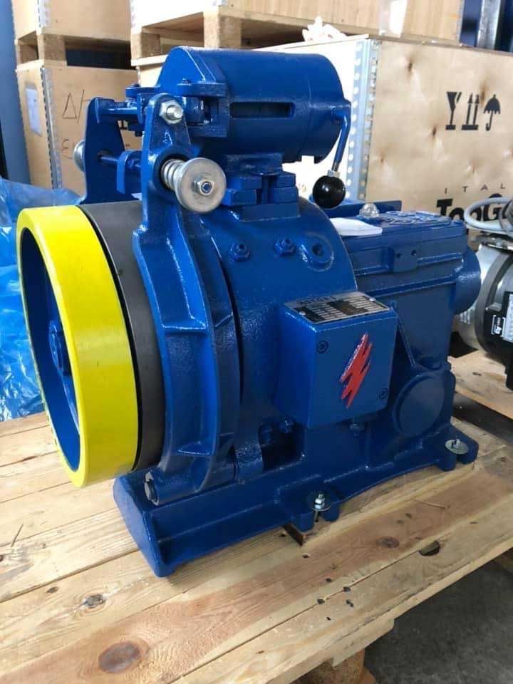 Μπλε βιομηχανική μηχανή με έναν μεγάλο κίτρινο σφόνδυλο σε μια ξύλινη παλέτα σε μια αποθήκη εμπορευμάτων