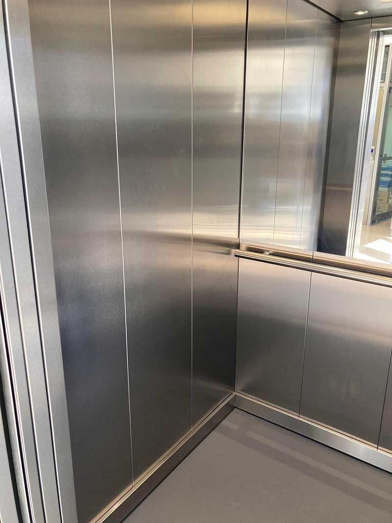 Άδειο εσωτερικό ανελκυστήρα από ανοξείδωτο χάλυβα με πίνακα ελέγχου και ανακλαστικούς μεταλλικούς τοίχους