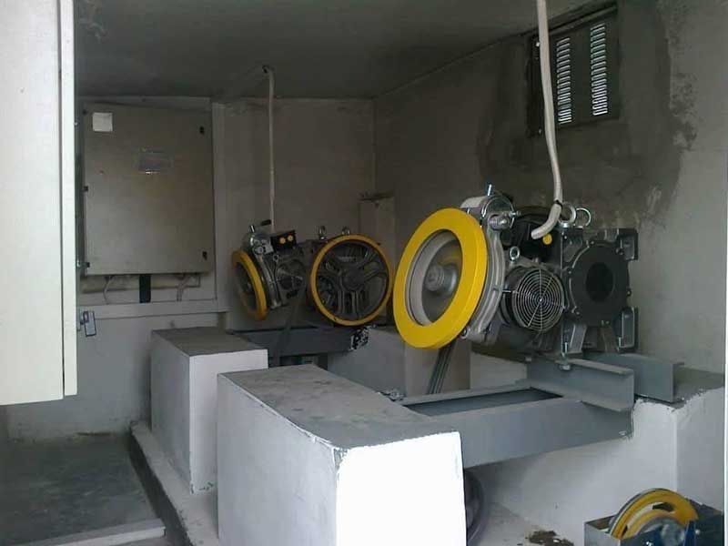 Βιομηχανικό δωμάτιο με μεγάλες κίτρινες μηχανές και λευκούς τσιμεντόλιθους μέσα σε έναν αμυδρό χώρο χρησιμότητας