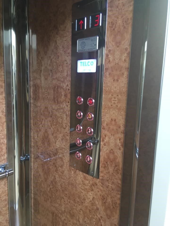 Πίνακας ελέγχου ανελκυστήρα με φωτιζόμενη οθόνη δαπέδου και κουμπιά σε τοίχο με ξύλινη επένδυση