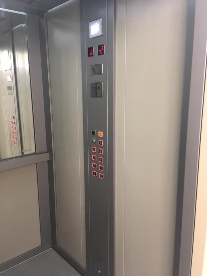 Εσωτερικό ανελκυστήρα με πίνακα ελέγχου, κουμπιά δαπέδου και πάνελ τοίχου με καθρέφτες.