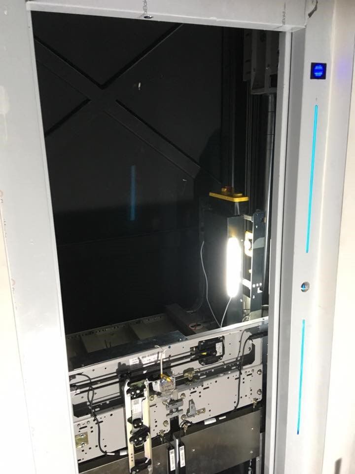 Ανοιχτό φρεάτιο ανελκυστήρα με εκτεθειμένα μηχανήματα, σκοτεινό εσωτερικό και φωτισμένο πίνακα ελέγχου στα δεξιά