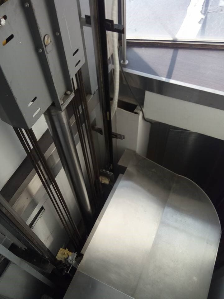 Εσωτερικό ενός σύγχρονου φρεατίου ανελκυστήρα με μεταλλικές ράγες και γκρι πάνελ.