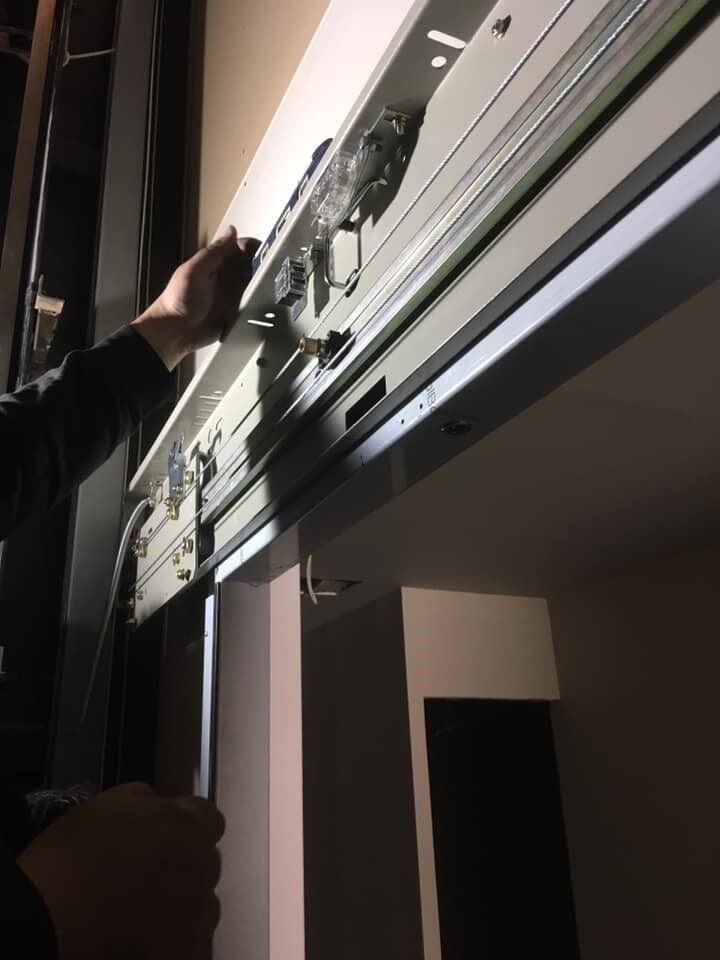 Άτομο που απλώνει το χέρι του για να ρυθμίσει ένα στόρι παραθύρου σε ένα δωμάτιο με χαμηλό φωτισμό.