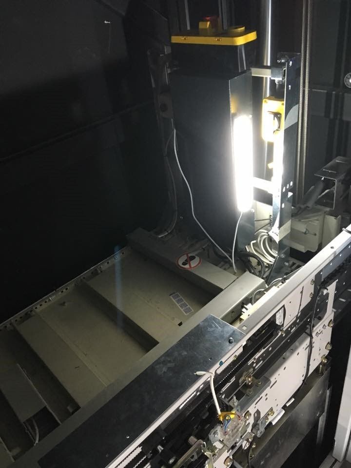 Εσωτερικό βιομηχανικού μηχανήματος με φωτεινό κάθετο φως και μεταλλικά πάνελ σε σκοτεινό χώρο εργασίας