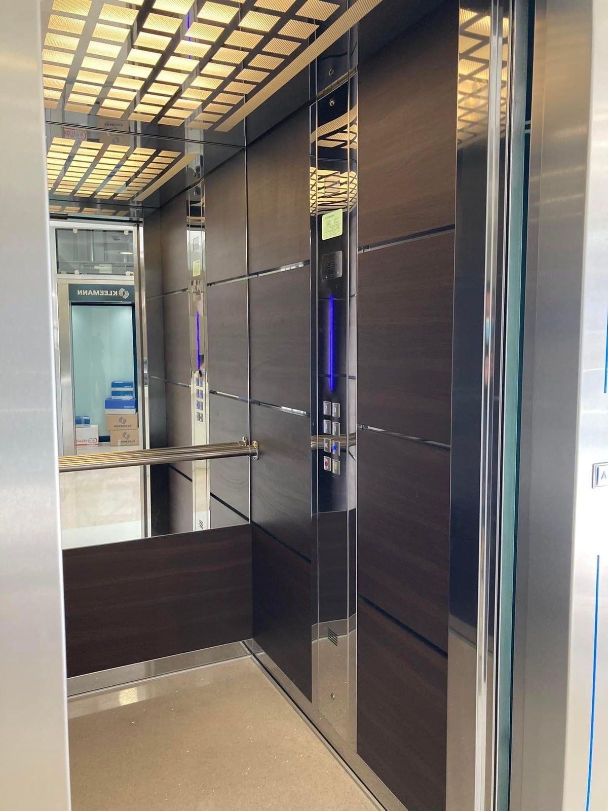 Σύγχρονο εσωτερικό ανελκυστήρα με σκούρα ξύλινα πάνελ, καθρέφτες στους τοίχους και φωτισμένο πίνακα ελέγχου