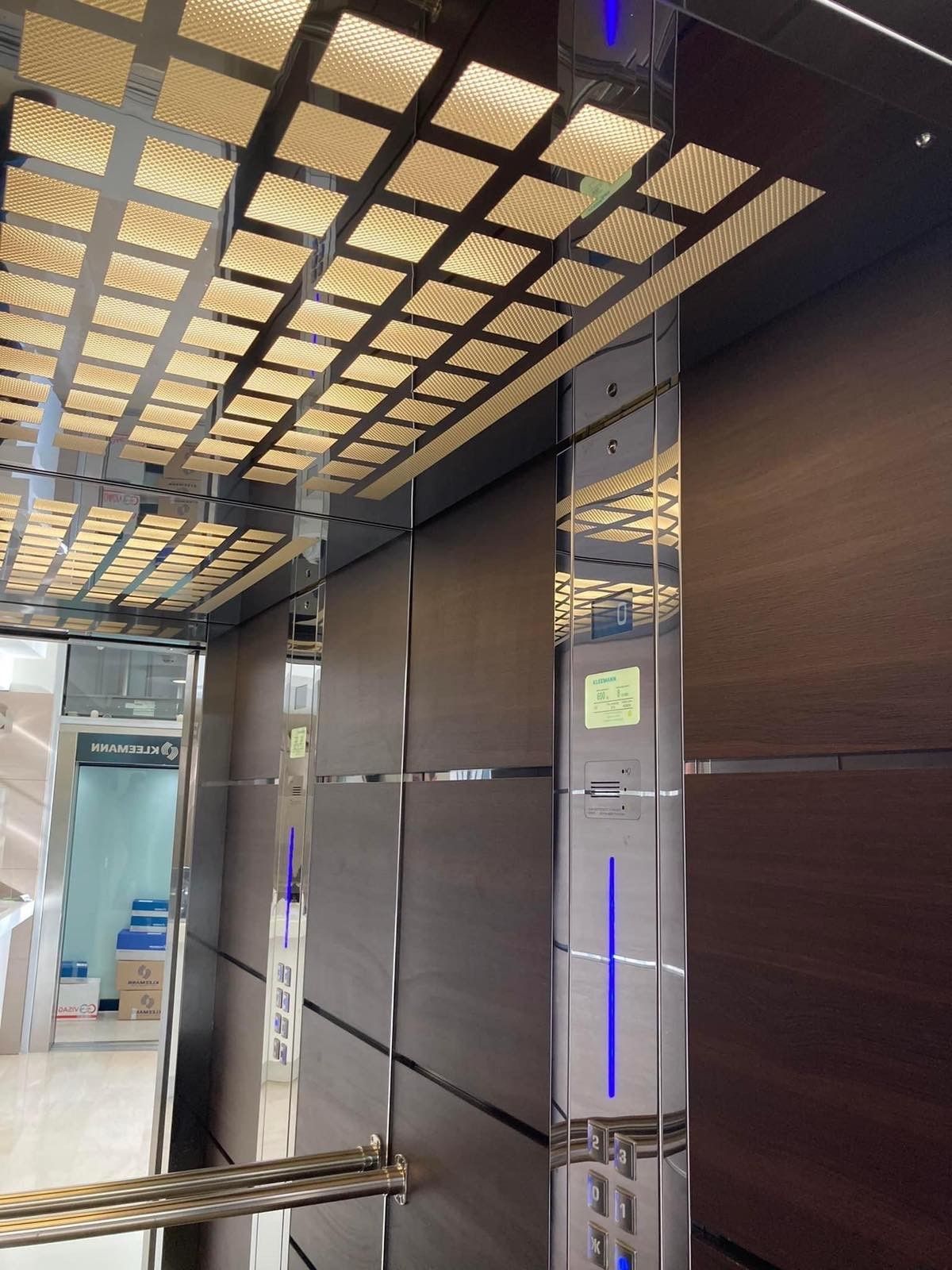 Σύγχρονο εσωτερικό ανελκυστήρα με καθρέφτες στους τοίχους, φωτεινά φώτα οροφής και πίνακα ελέγχου με μπλε φωτισμό