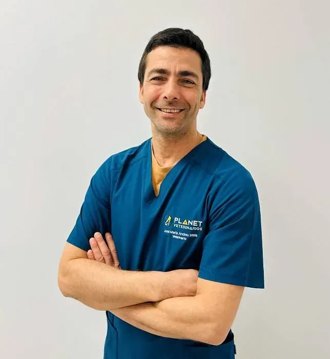 Un hombre con un uniforme azul está de pie, con los brazos cruzados y sonriendo.