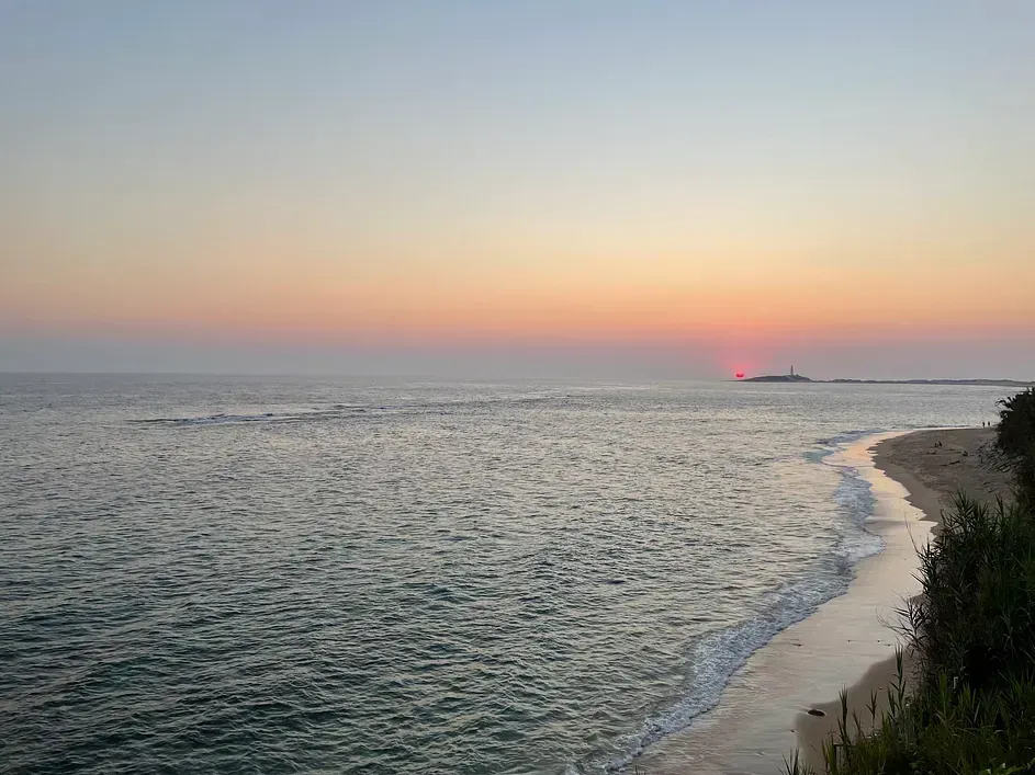 Una puesta de sol sobre el océano con un barco en la distancia