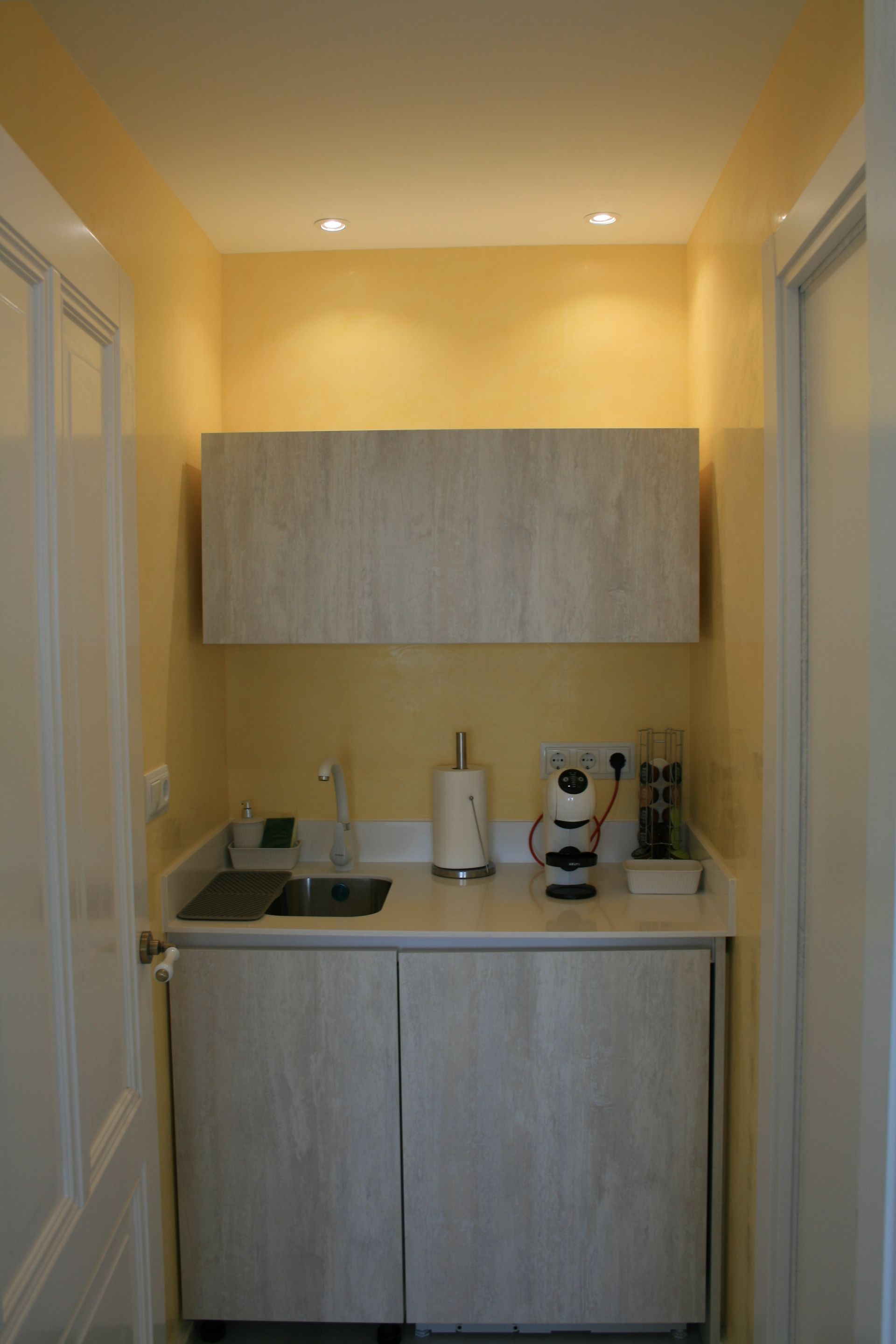 Una pequeña cocina con gabinetes blancos y un fregadero.