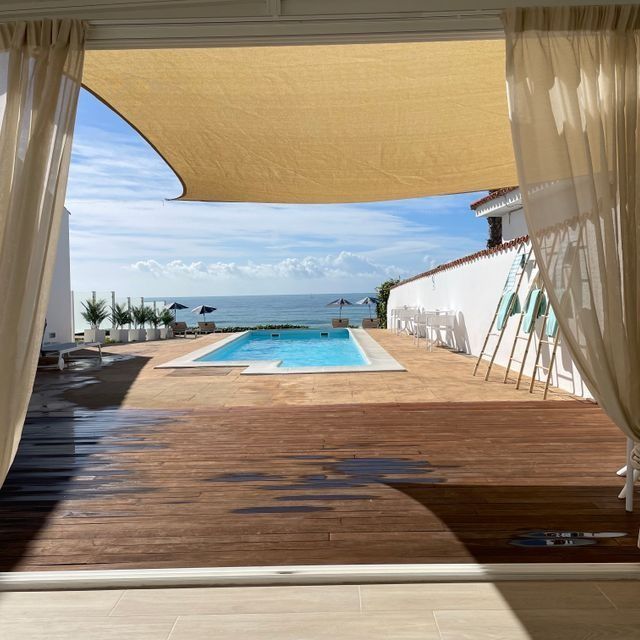 Una vista de una piscina y el océano a través de una ventana.