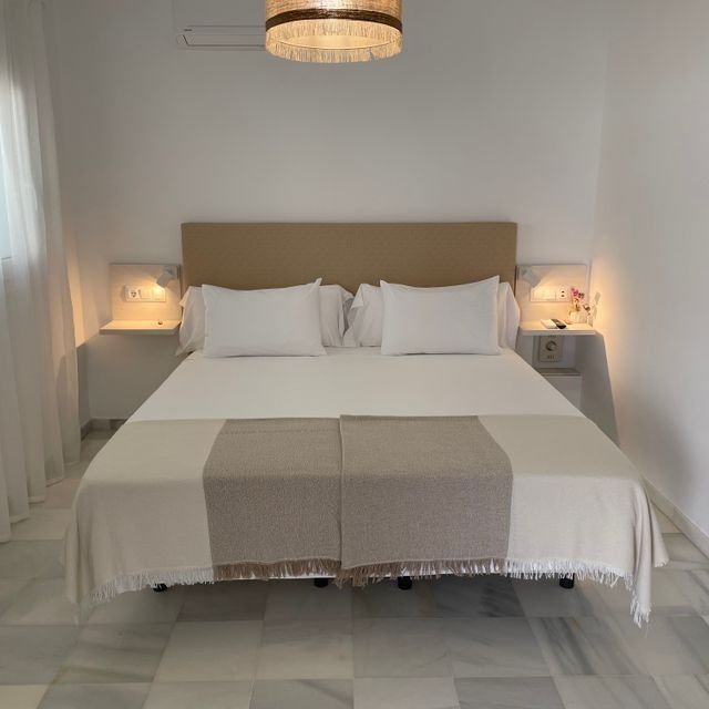 Un dormitorio con una cama grande y una lámpara colgando del techo.