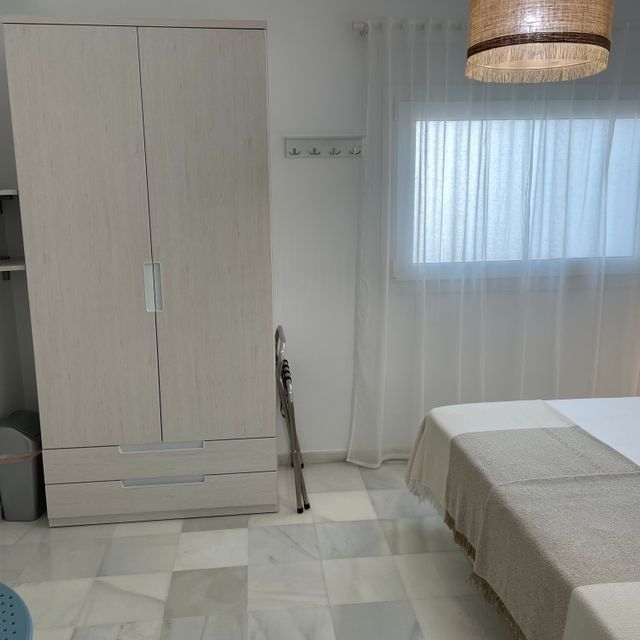 Un dormitorio con dos camas, un armario y una ventana.