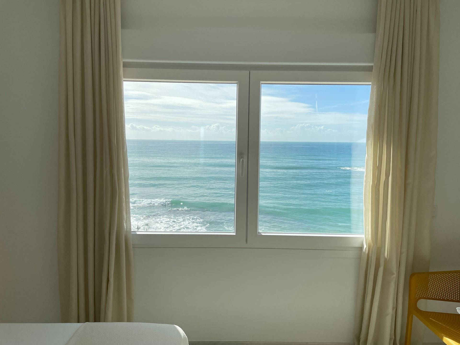 Un dormitorio con una gran ventanal con vistas al océano.