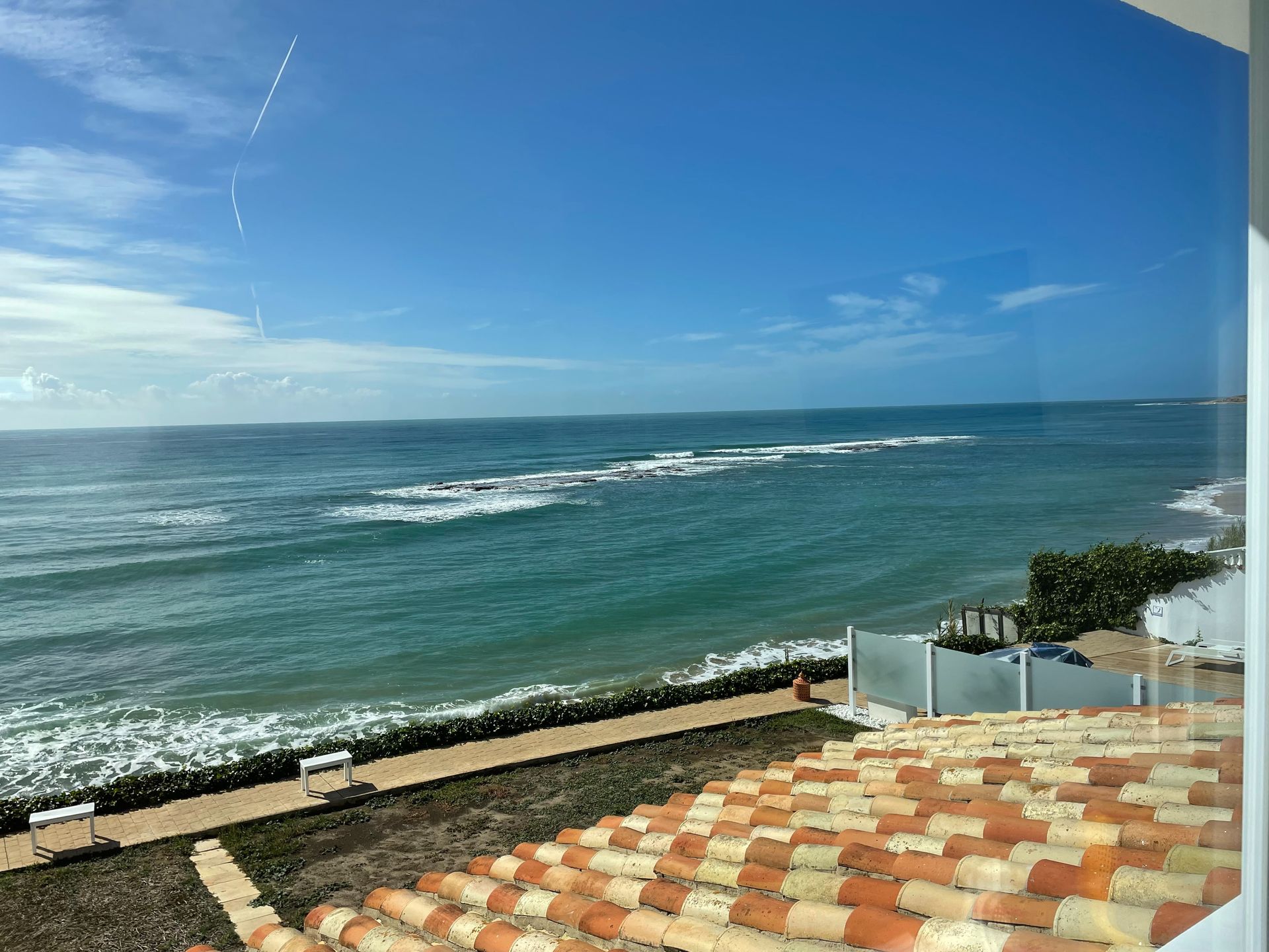 Una vista del océano desde un balcón con techo de tejas.
