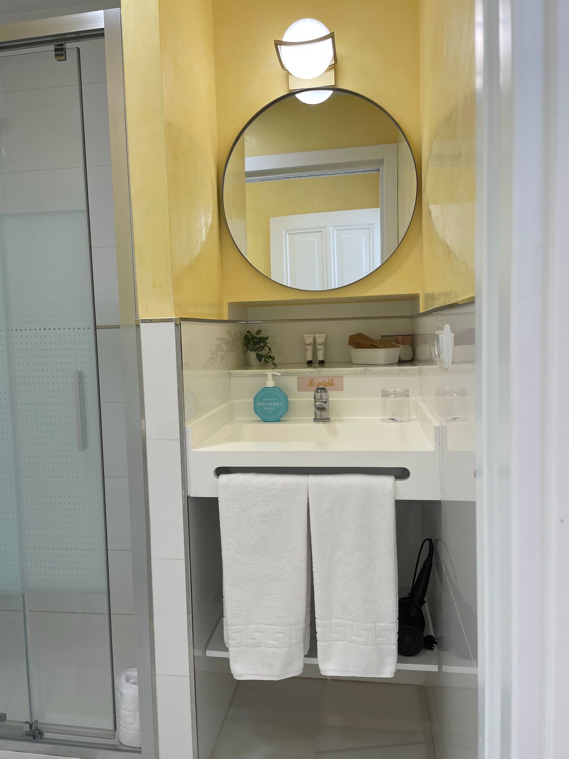 Un baño con lavabo y espejo redondo.