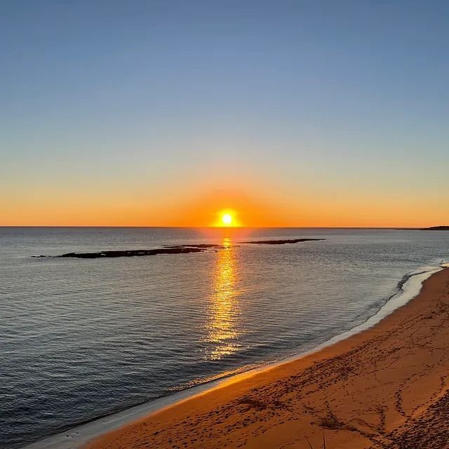 El sol se está poniendo sobre el océano en una playa.