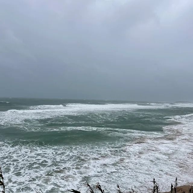 Una gran masa de agua con olas rompiendo en la orilla en un día nublado.