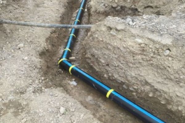 Ein schwarz-blaues Rohr wird im Boden verlegt. Foto von Höchner Sanitär Heizung