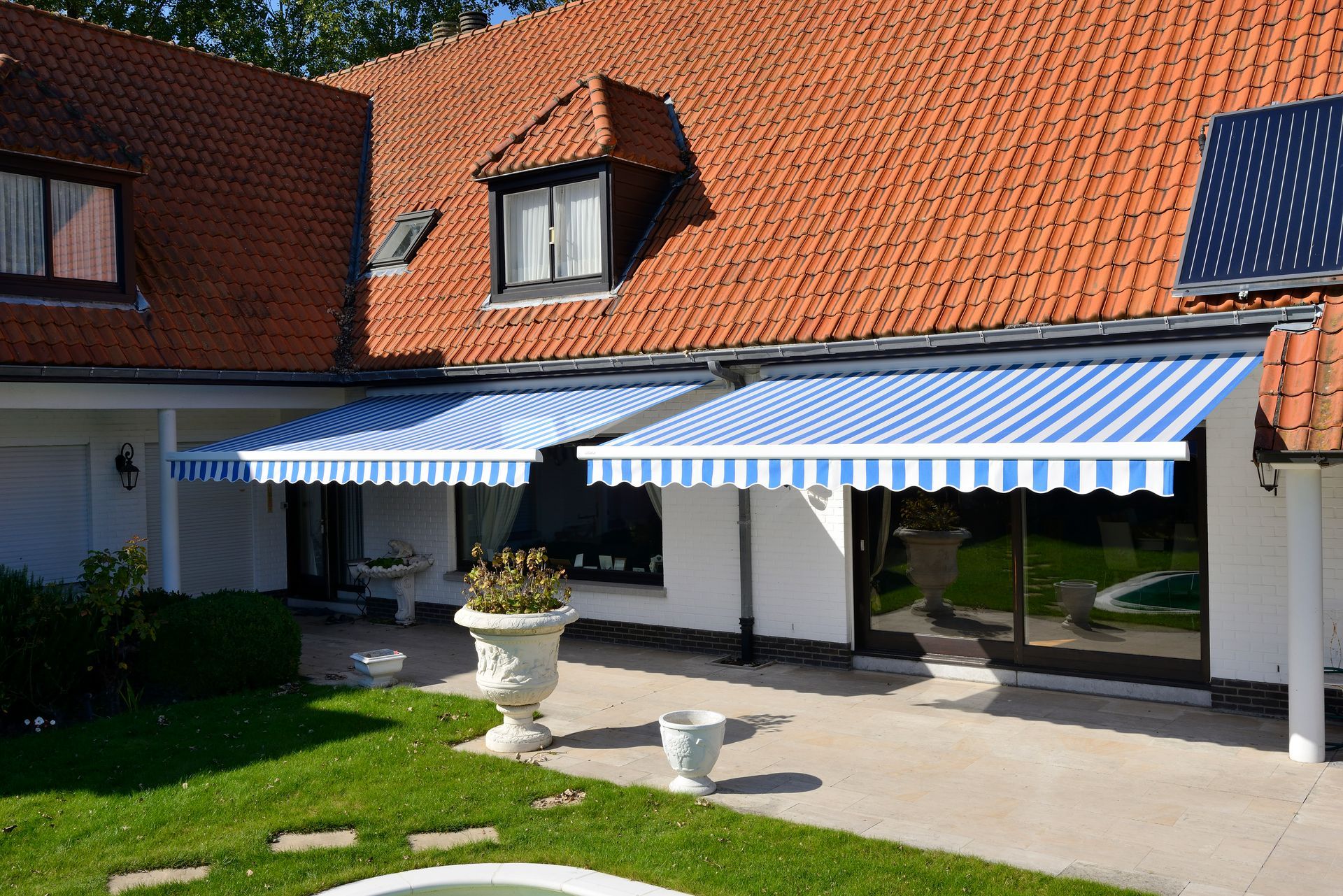 Deux stores bannes aux rayures bleu et blanc d'une grande maison