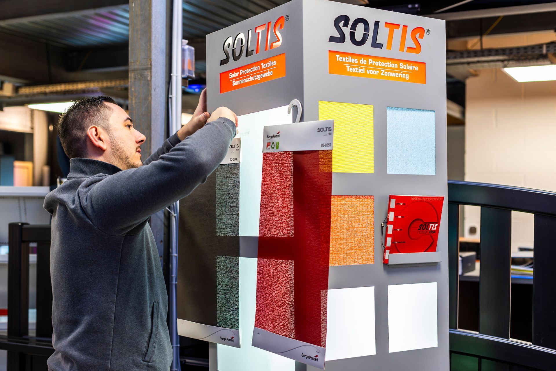 Une personne de chez Godstore en train d'accrocher des échantillons de tissus colorés