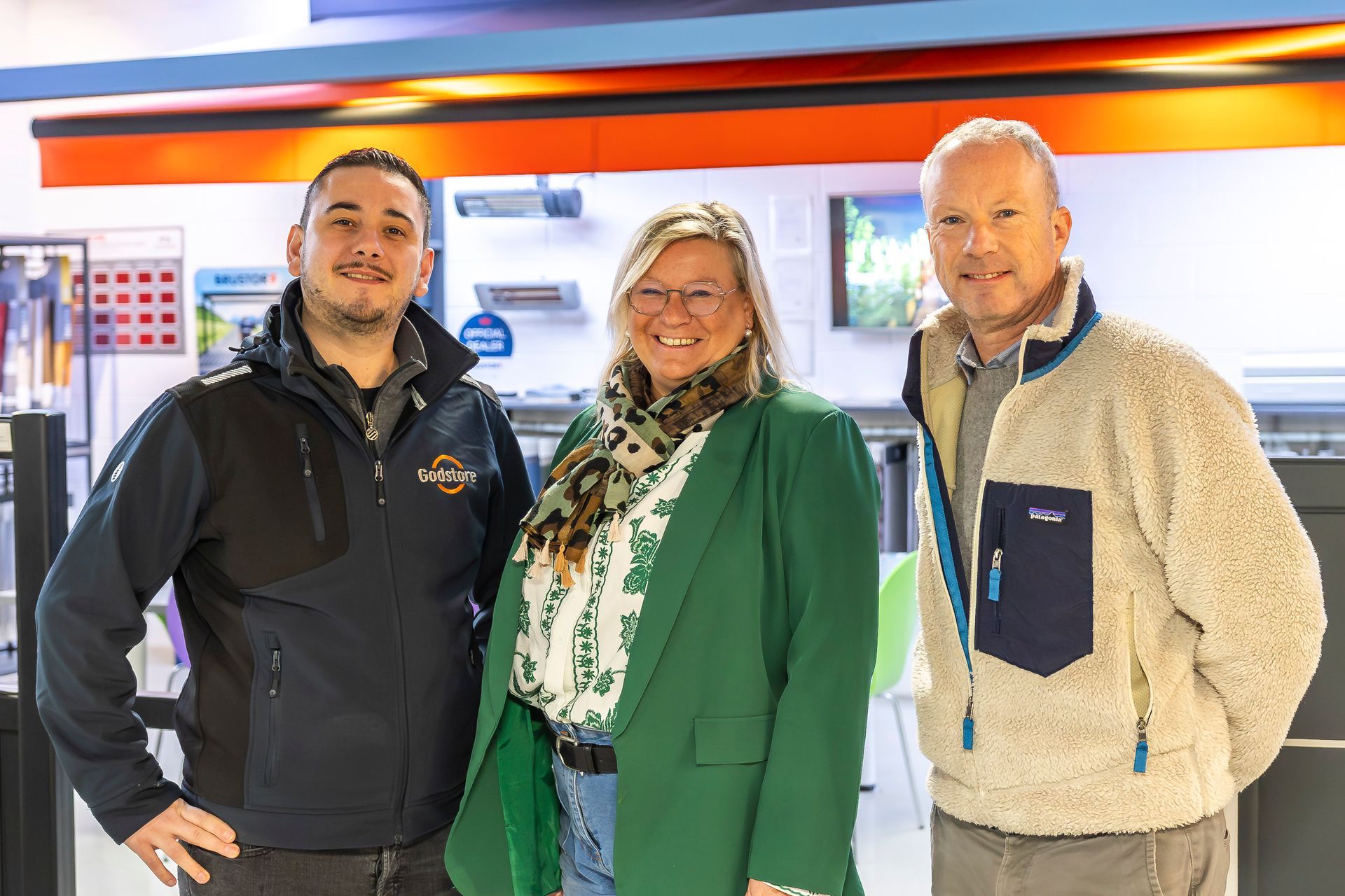 Deux hommes et une femme souriants de chez Godstore posant devant l'objectif