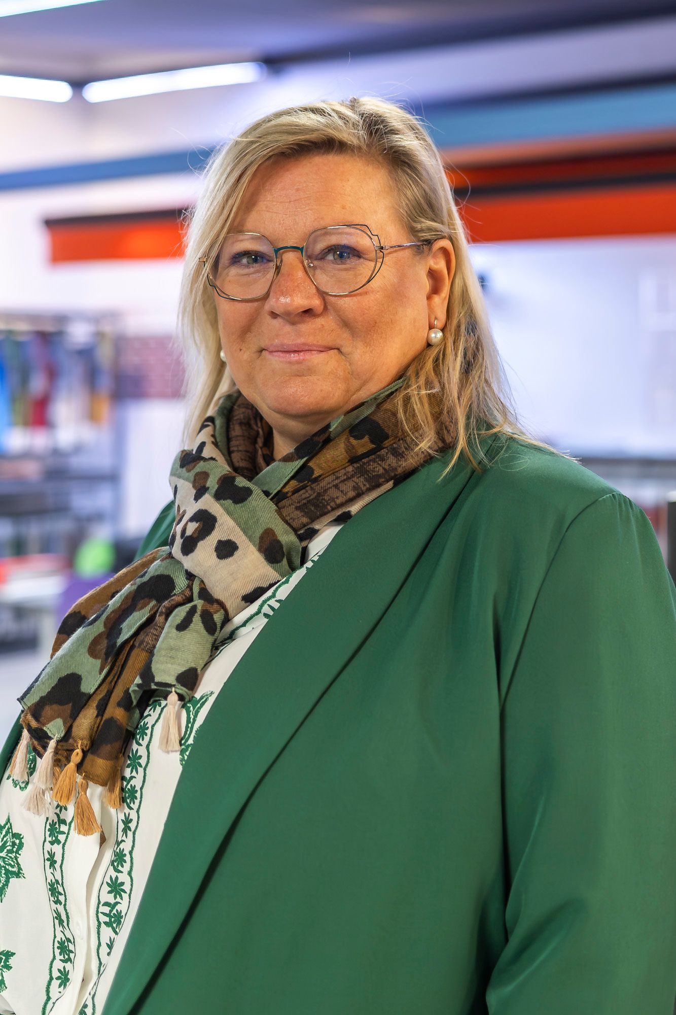 Une dame souriante portant une écharpe et une veste verte