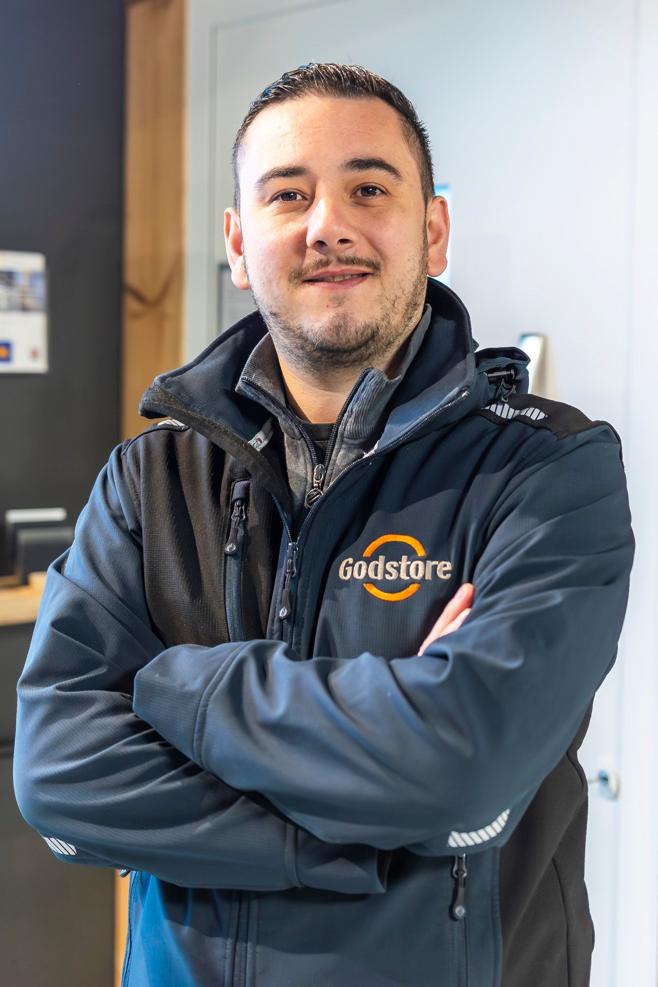 Un homme souriant portant un blouson estampillé Godstore