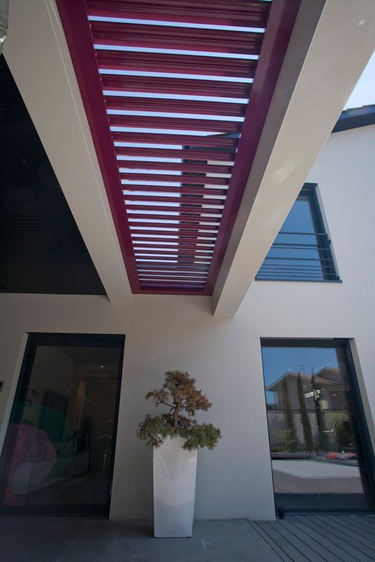 Pergola encastré entre deux piliers en béton d'une maison