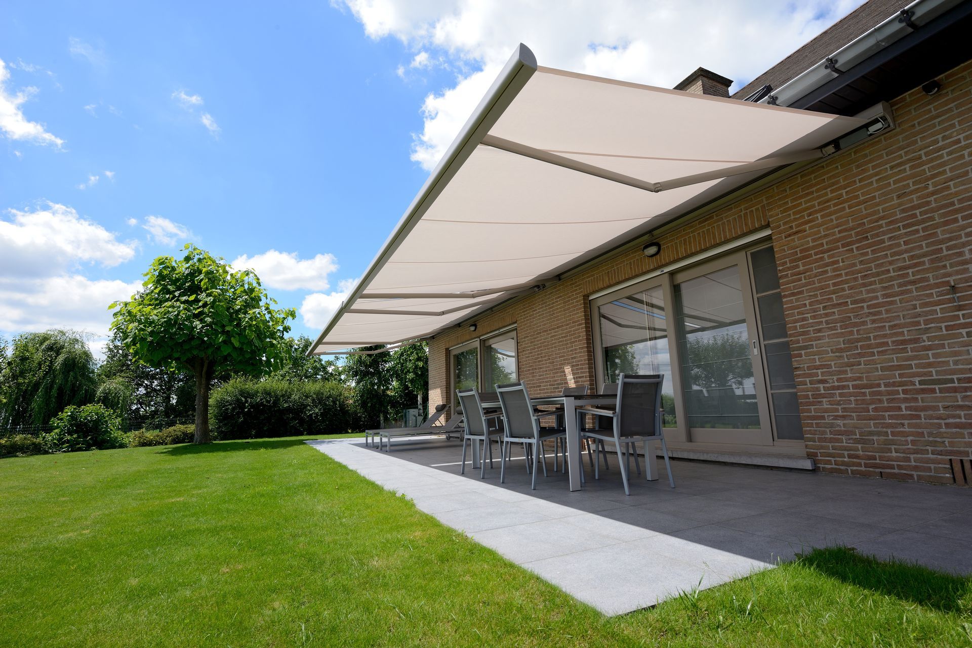 Dessous d'une terrasse avec table et chaise sous un store banne ouvert
