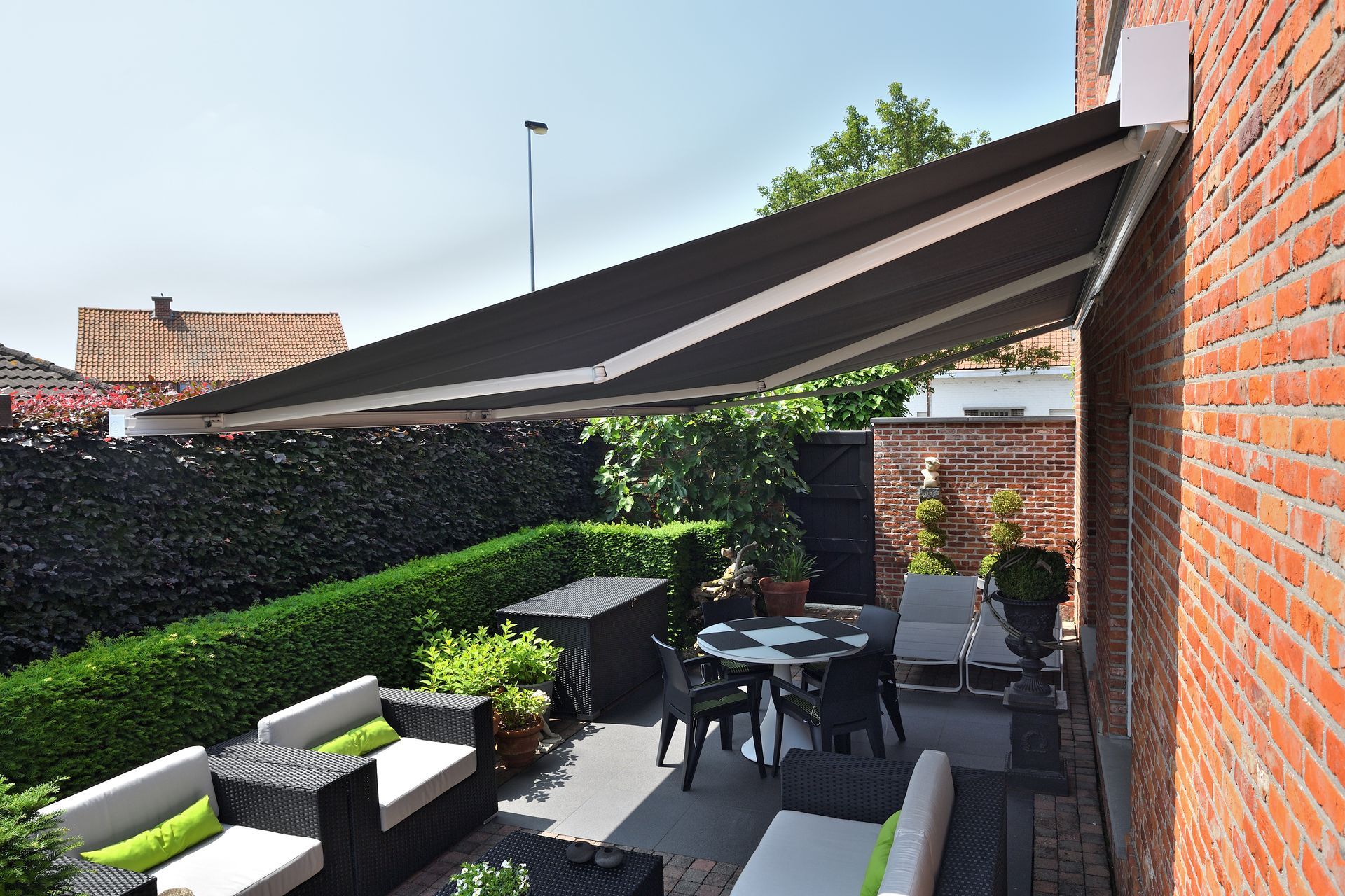 Terrasse équipée de plusieurs siège et table sous un grand store banne