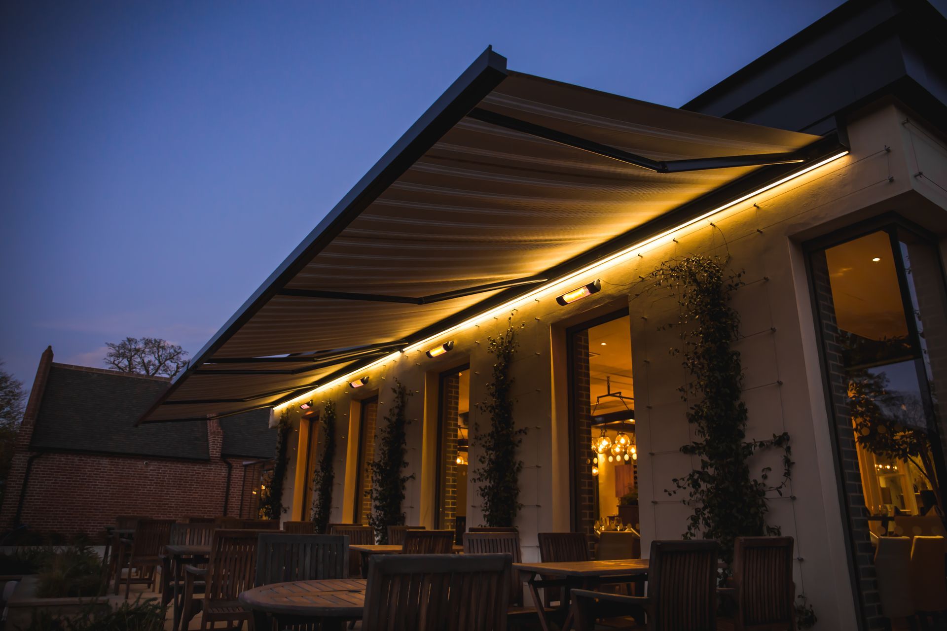 Autre vue des stores bannes éclairés sur une terrasse de restaurant le soir