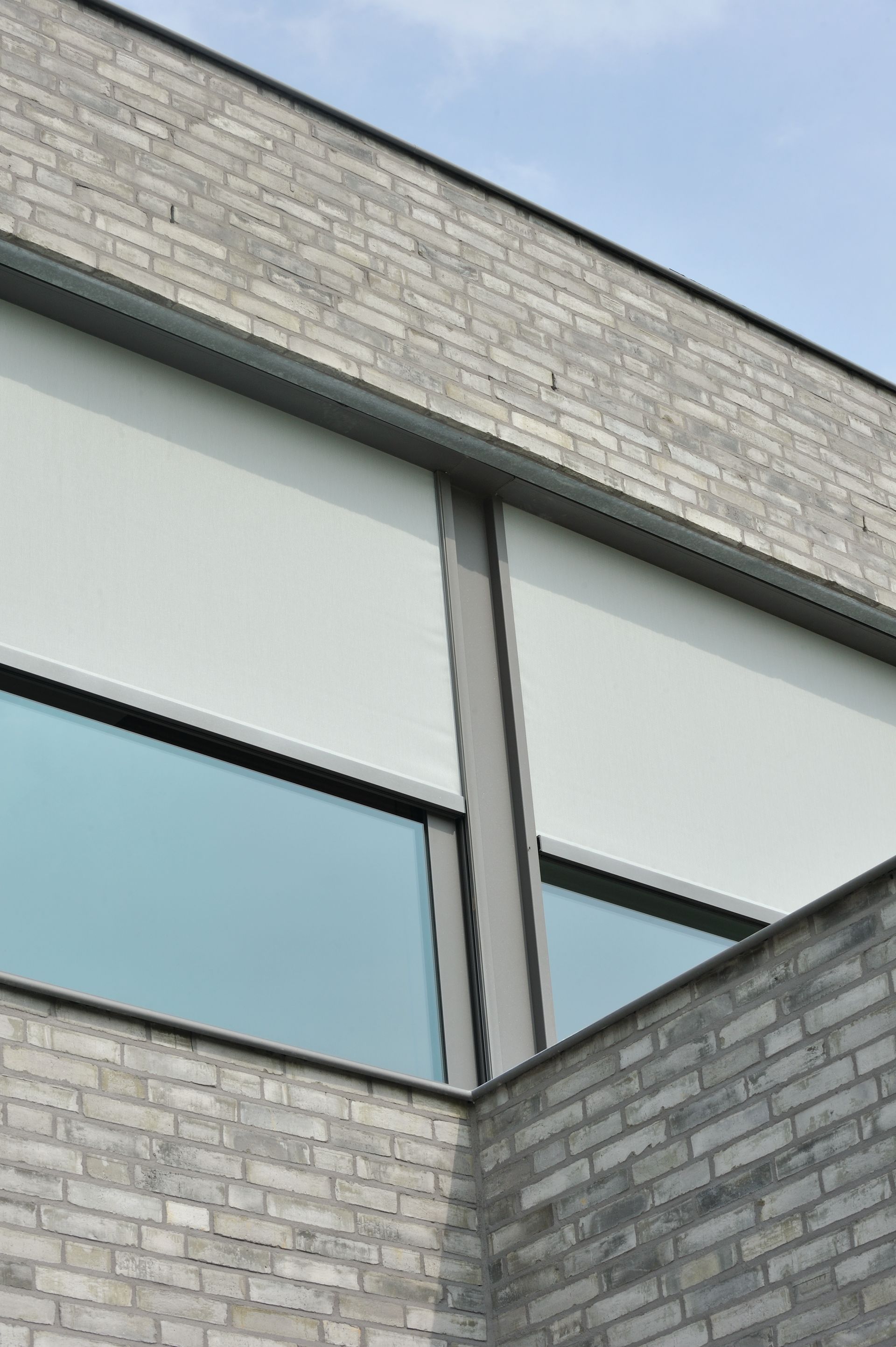 Deux stores extérieurs à moitié fermés aux fenêtres d'un étage