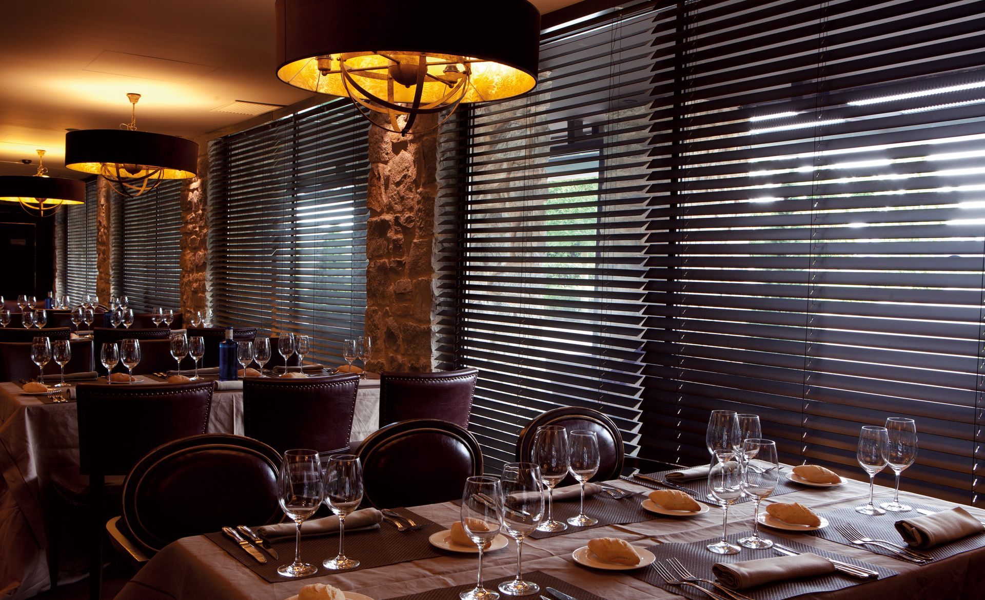 Intérieur d'un restaurant avec plusieurs couverts sur les tables aux stores intérieurs fermés