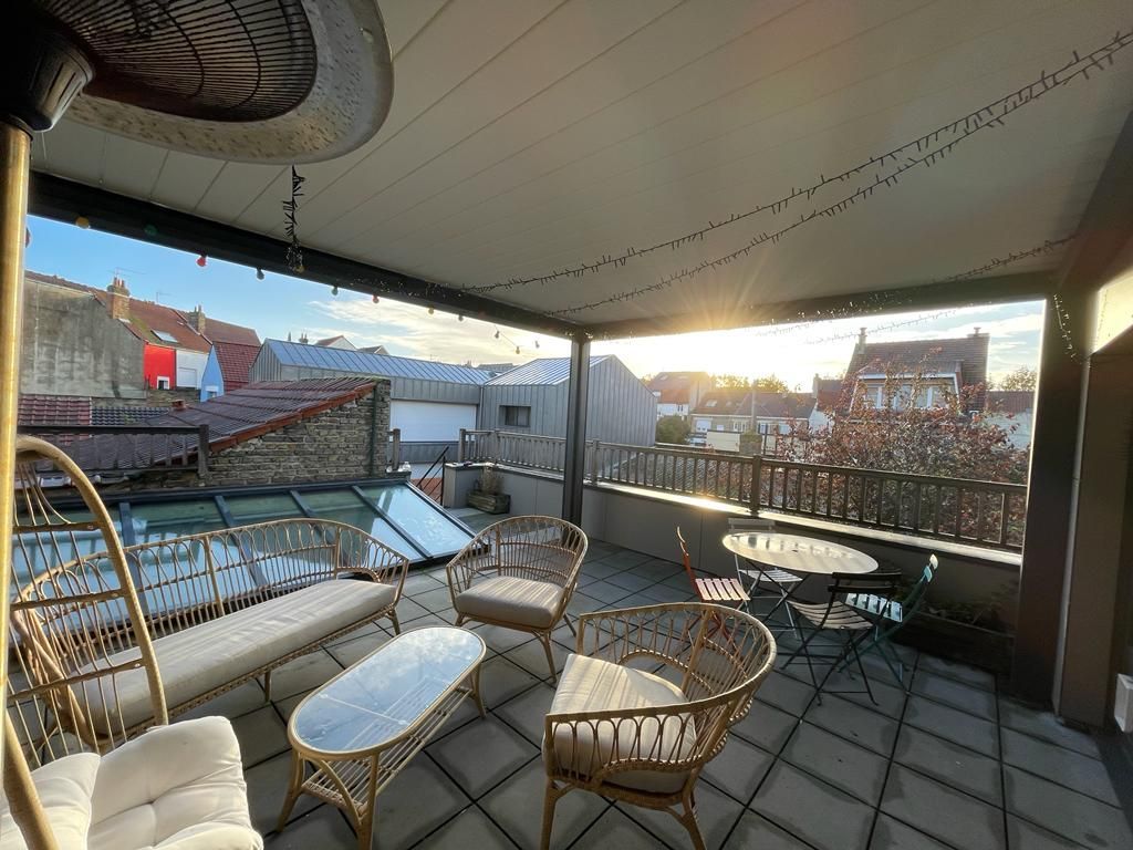 Terrasse sous une pergola à l'étage d'un immeuble donnant vue sur la ville