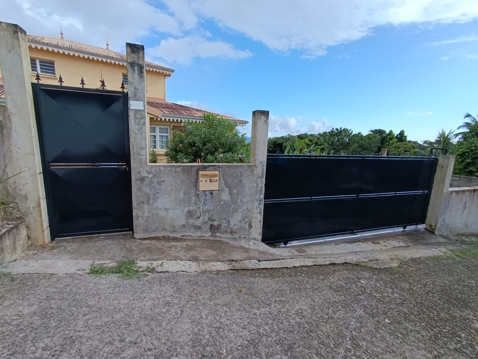 Portillon et portail noir séparés par un muret en béton