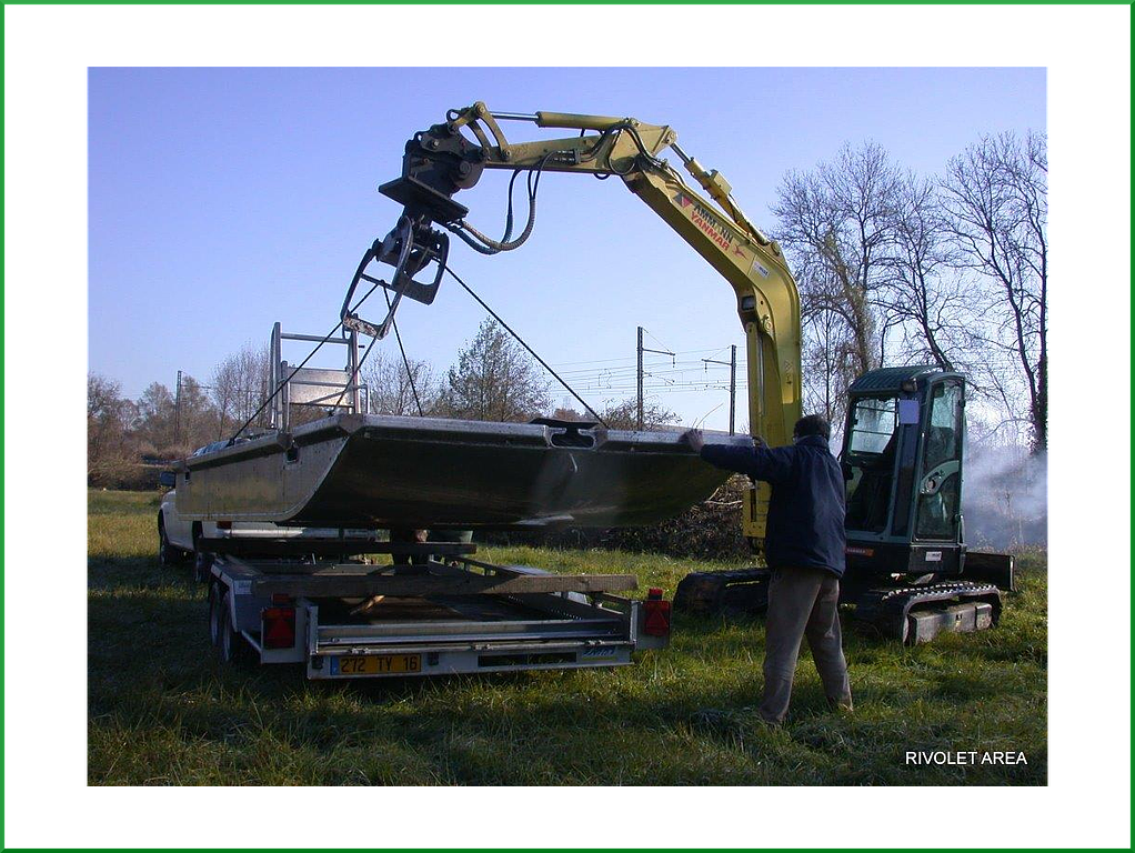 Machine de TP jaune en train de tenir une barque
