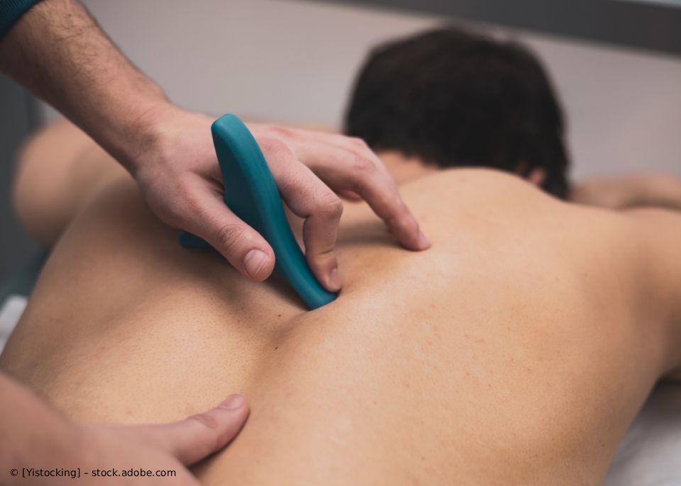 Person erhält eine Rückenmassage mit einem blauen Massagegerät.