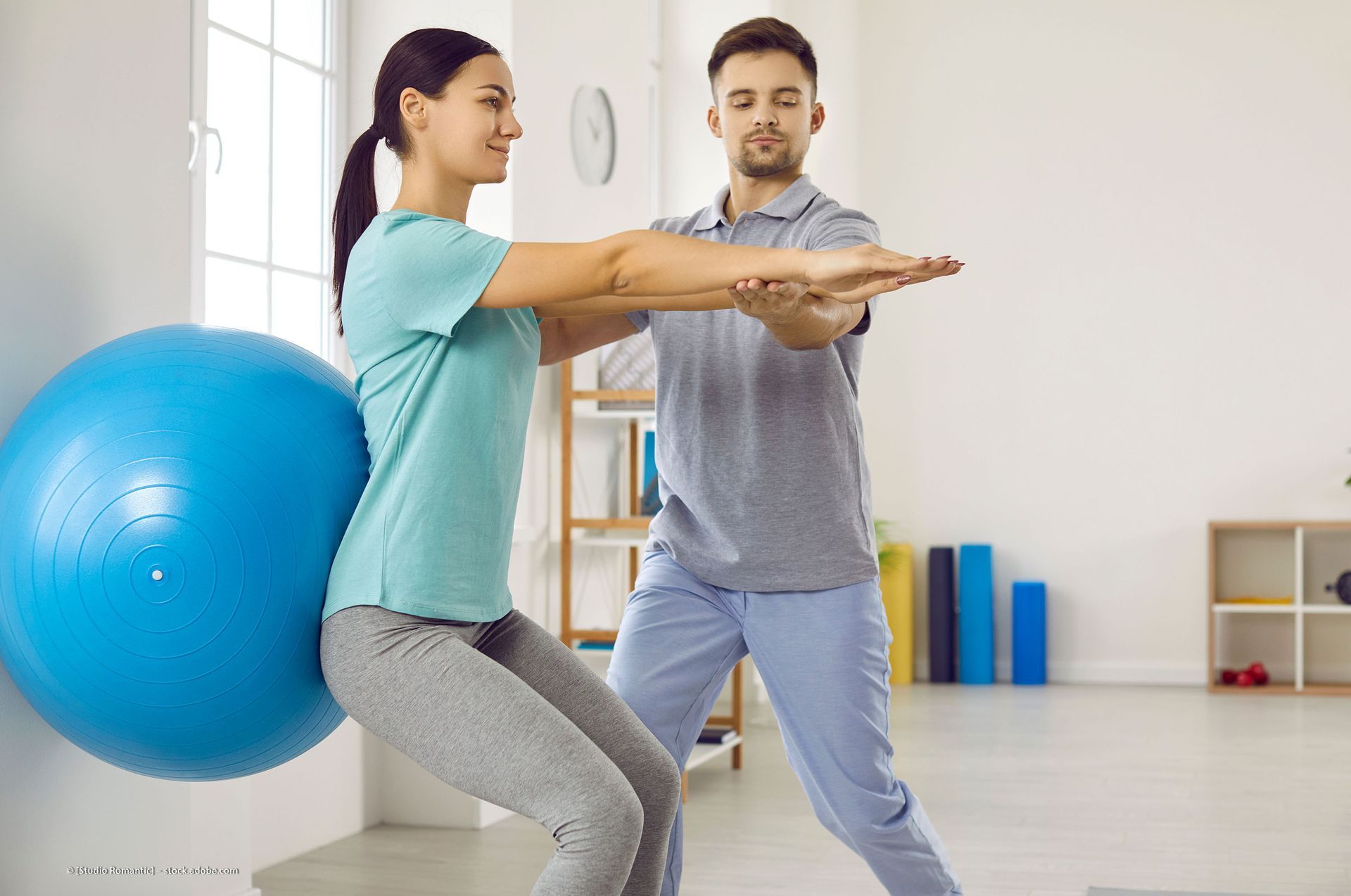 Eine Person erhält in einem Innenraum Physiotherapie für ihr Bein. Der Therapeut trägt blaue OP-Kleidung.