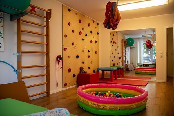 Fitnessraum mit Kletterwand, Bällebad und Trainingsgeräten.
