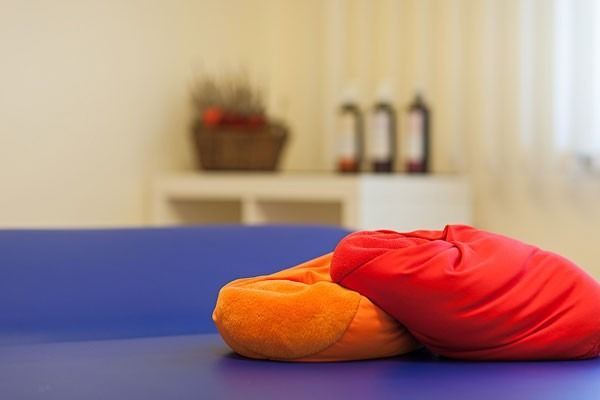 Orange und rote Sitzsäcke liegen auf einer blauen Fläche, im Hintergrund ist ein Zimmer verschwommen zu sehen.